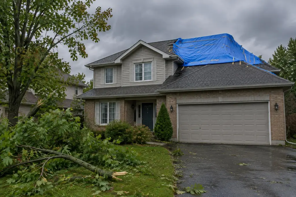 A blue tarp temporarily covering storm damage on a two-storey suburban Ontario home